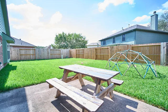a view of a backyard with table and chairs with a barbeque grill and a small yard