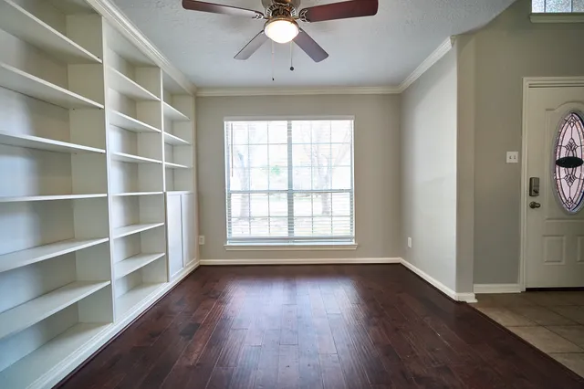 a view of an empty room with a window and wooden floor