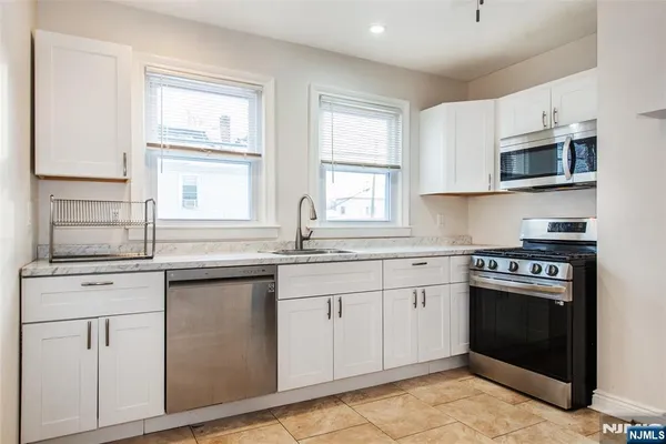 a kitchen with stainless steel appliances granite countertop a stove and white cabinets