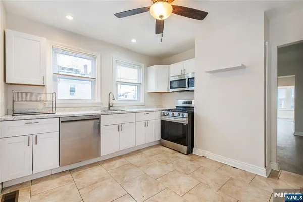 a kitchen with granite countertop a sink cabinets stainless steel appliances and a window