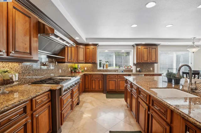 a kitchen with stainless steel appliances granite countertop a sink stove and cabinets