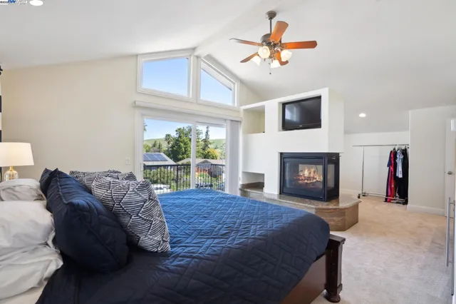 a spacious bedroom with a bed a fireplace and a television