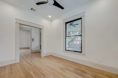 an empty room with wooden floor and windows
