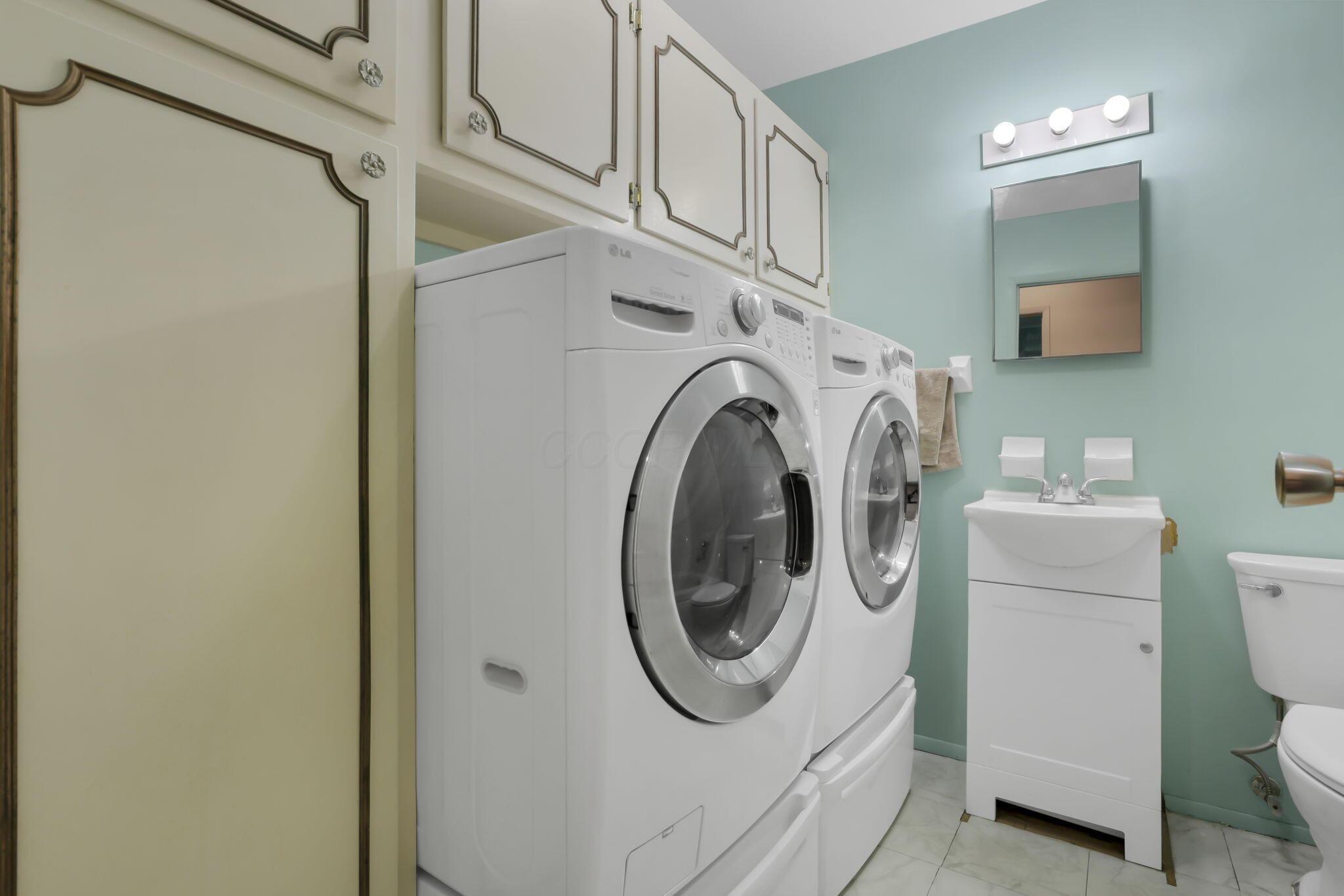 3882 Glenfield Road Columbus, OH 43232 - Photo 16 of 29 Laundry area with stacked appliances, cream cabinetry with detailed trim, a wall-mounted vanity mirror, a single-basin sink with storage, and a light-colored tile floor