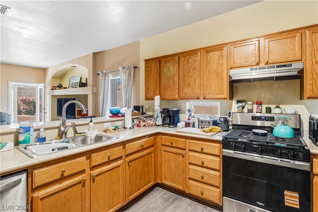 2823 Rippling Springs Street Laughlin, NV 89029 - Photo 14 of 89 Kitchen featuring stainless steel appliances, light countertops, a fireplace, and wood finish cabinetry