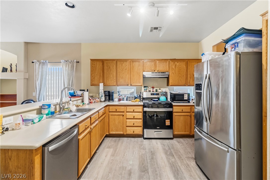 2823 Rippling Springs Street Laughlin, NV 89029 - Photo 16 of 89 Kitchen with stainless steel appliances, light countertops, light wood finished floors, a peninsula, and wood finish cabinets
