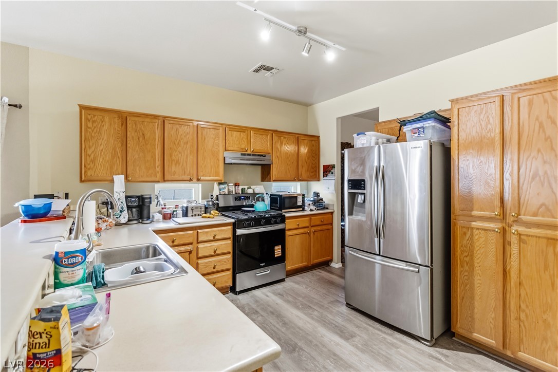 2823 Rippling Springs Street Laughlin, NV 89029 - Photo 17 of 89 Kitchen featuring stainless steel appliances, light countertops, light wood-style flooring, a peninsula, and track lighting