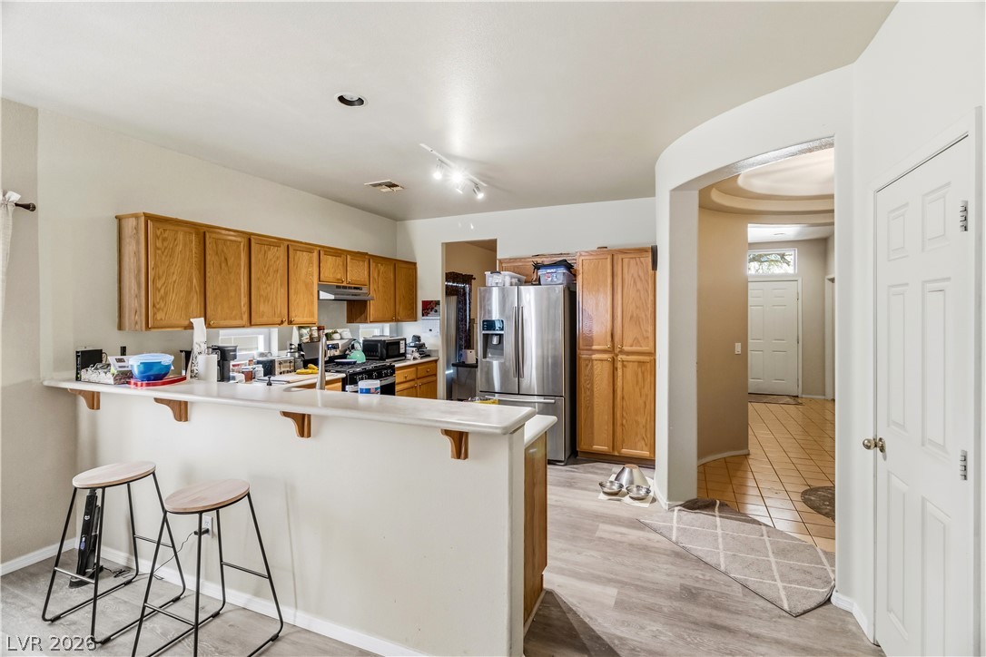 2823 Rippling Springs Street Laughlin, NV 89029 - Photo 18 of 89 Kitchen featuring a peninsula, wood finish cabinets, a kitchen breakfast bar, light countertops, and stainless steel appliances