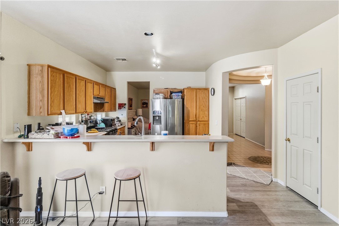 2823 Rippling Springs Street Laughlin, NV 89029 - Photo 19 of 89 Kitchen with a peninsula, a breakfast bar area, stainless steel appliances, light countertops, and wood finish cabinets