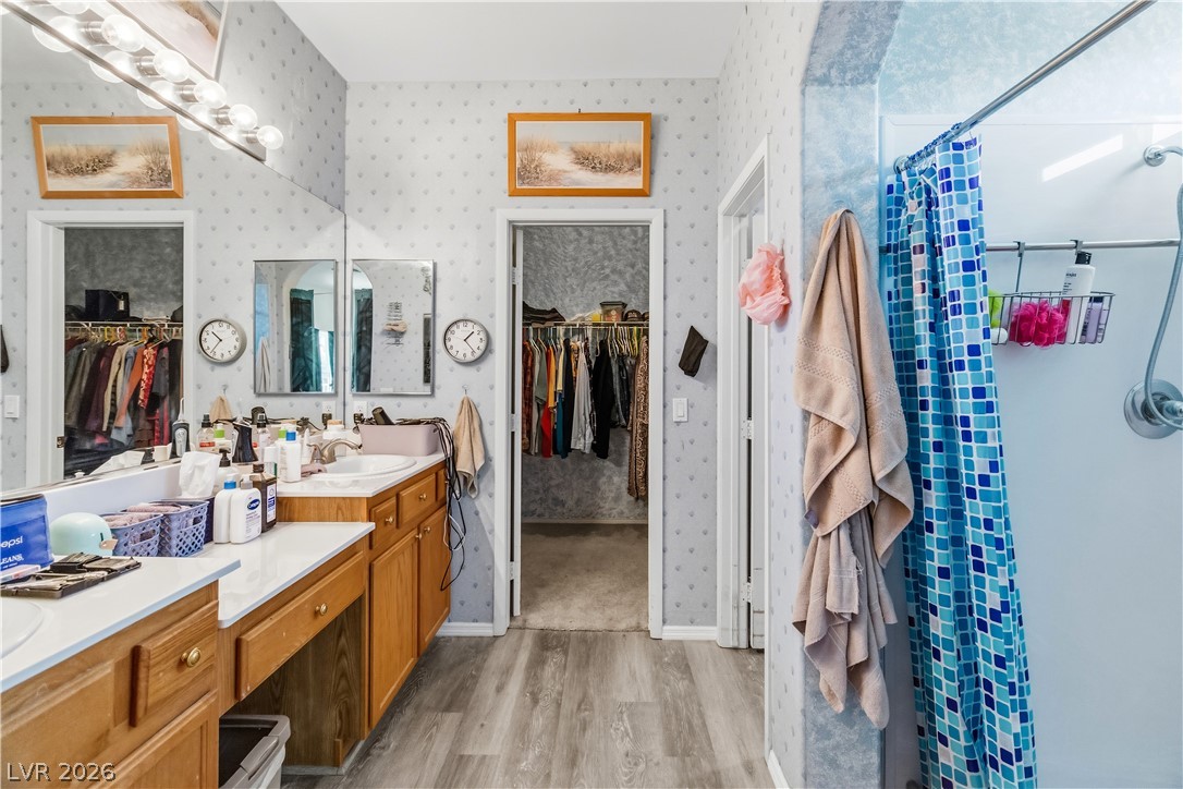 2823 Rippling Springs Street Laughlin, NV 89029 - Photo 31 of 89 Primary Bathroom with a spacious closet, vanity, light wood-style floors, a large walk-in shower, and wallpapered walls