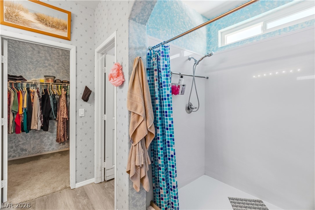 2823 Rippling Springs Street Laughlin, NV 89029 - Photo 32 of 89 Primary Bathroom with a large walk-in shower, wallpapered walls, a walk in closet, and light wood-style flooring