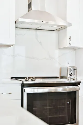 a kitchen with stainless steel appliances granite countertop a refrigerator a stove and white cabinets