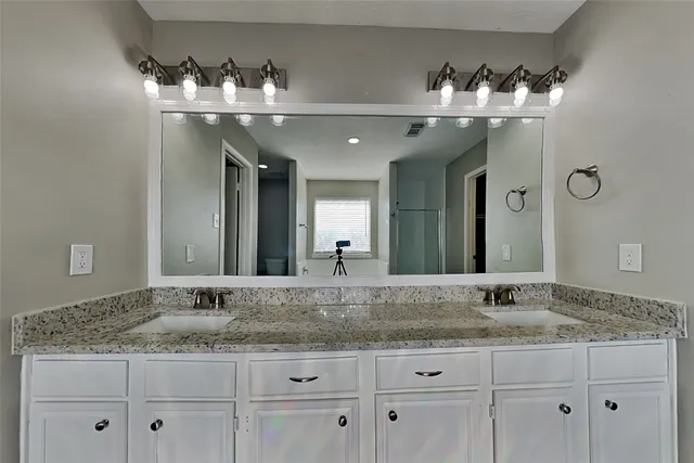 a bathroom with double vanity sinks and a mirror