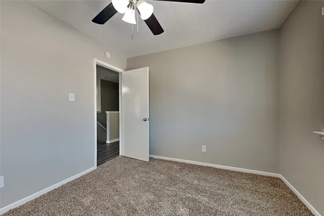 an empty room with a ceiling fan and carpet