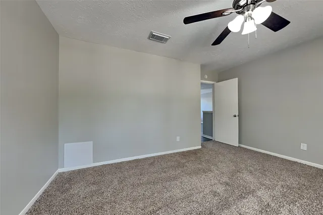a view of an empty room and chandelier fan