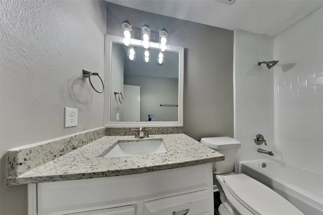 a bathroom with a granite countertop sink a toilet and a mirror