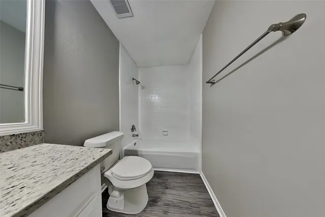 a bathroom with a granite countertop sink a toilet and shower