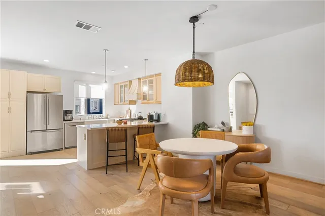 a kitchen with a dining table chairs a sink dishwasher a refrigerator and microwave with wooden floor