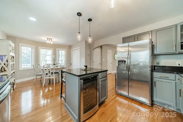 a kitchen with stainless steel appliances granite countertop a stove refrigerator and a dining table with wooden floor