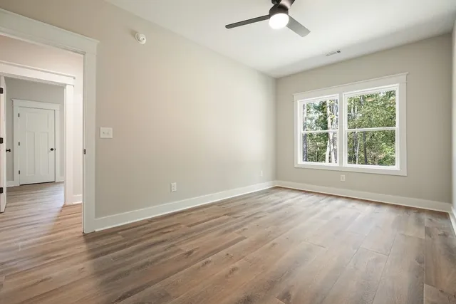 a view of empty room with wooden floor and fan