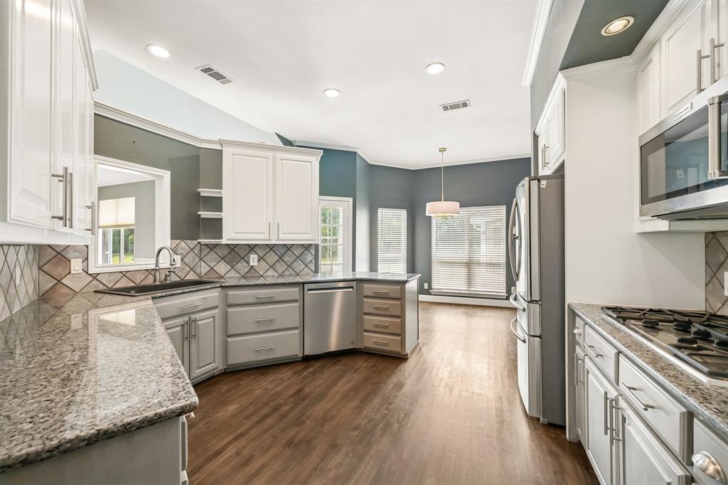 1380 Meandro Ria Lane Fairview, TX 75069 - Photo 10 of 39 Kitchen featuring white cabinetry, granite countertops, stainless steel appliances, wood-finish flooring, and a decorative tile backsplash