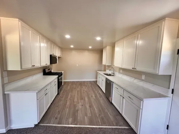 a large kitchen with a large counter top a sink a stove and wooden floor
