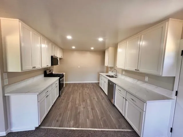 a large kitchen with a large counter top a sink a stove and wooden floor