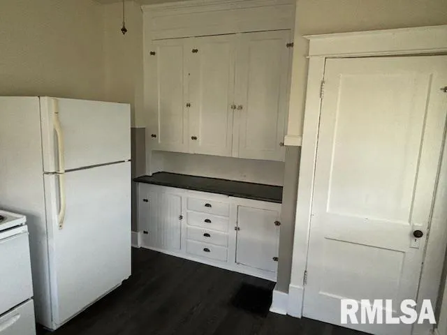 a view of a refrigerator in kitchen and white cabinets