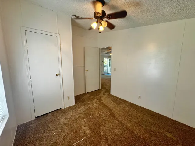 an empty room with closet and a chandelier fan