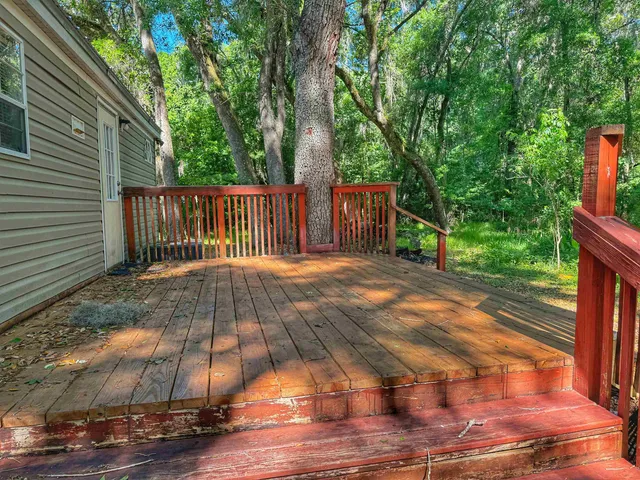 a view of backyard with wooden floor and fence