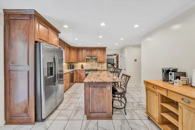 a kitchen with stainless steel appliances granite countertop a refrigerator and a stove top oven