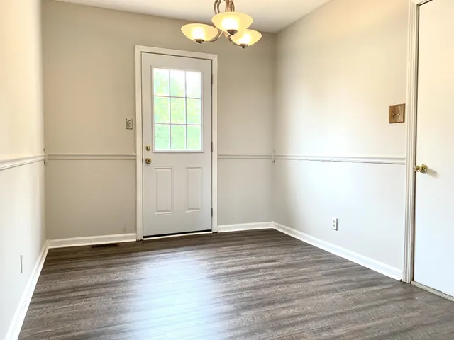 an empty room with wooden floor cabinet and windows