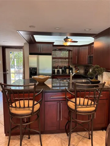 a kitchen with a stove a window and chairs