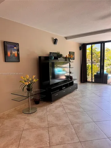 a living room with furniture a flat screen tv and floor to ceiling window