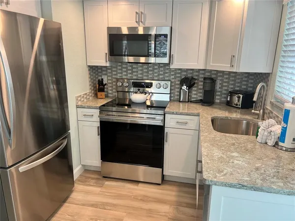 a kitchen with stainless steel appliances granite countertop a refrigerator stove and sink