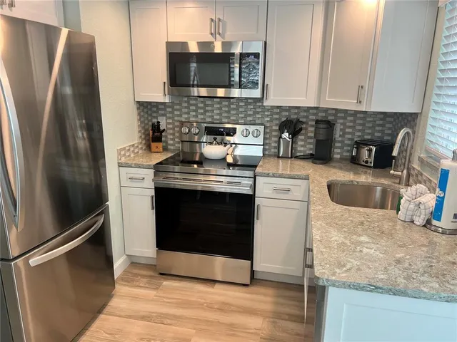 a kitchen with stainless steel appliances granite countertop a refrigerator stove and sink