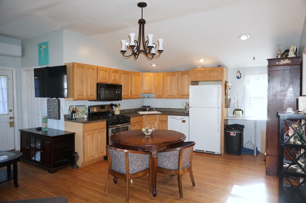 9 Circuit Road West Yarmouth, MA 02673 - Photo 9 of 23 a kitchen with stainless steel appliances granite countertop a refrigerator a stove top oven a sink dishwasher a dining table and chairs with wooden floor