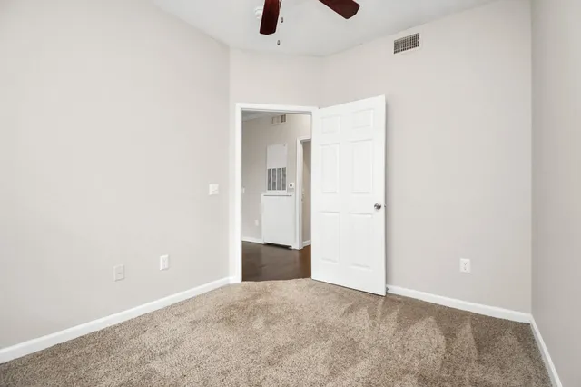 an empty room with ceiling fan and window