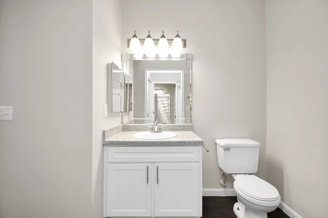 a bathroom with a toilet sink vanity granite and mirror