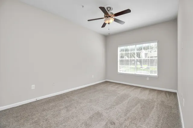an empty room with a window and a fan