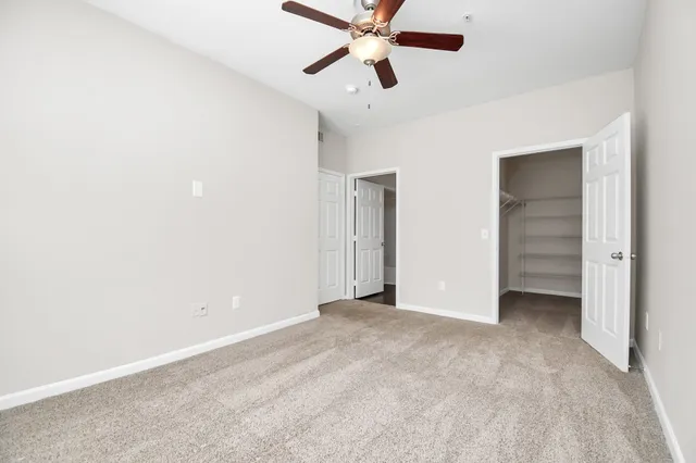 an empty room with closet and a ceiling fan