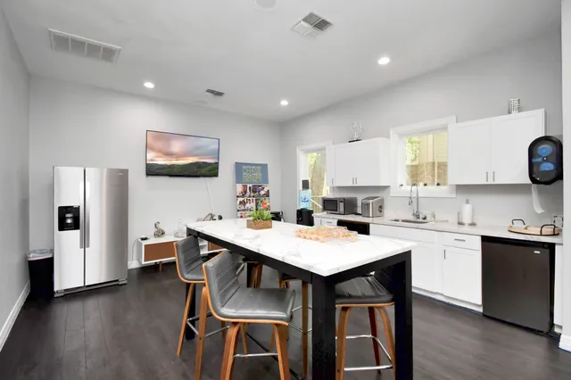 a kitchen with a dining table chairs and refrigerator