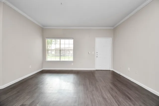 a view of an empty room with wooden floor and window