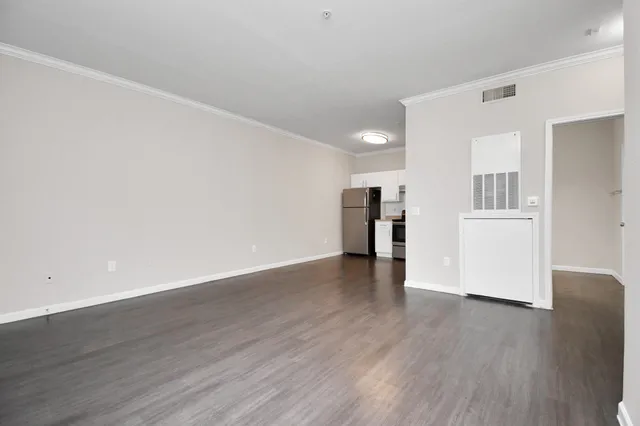 a view of a big room with wooden floor and a kitchen
