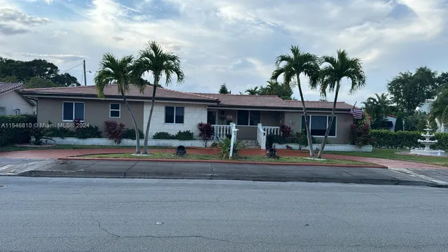 front view of house with a yard and palm trees