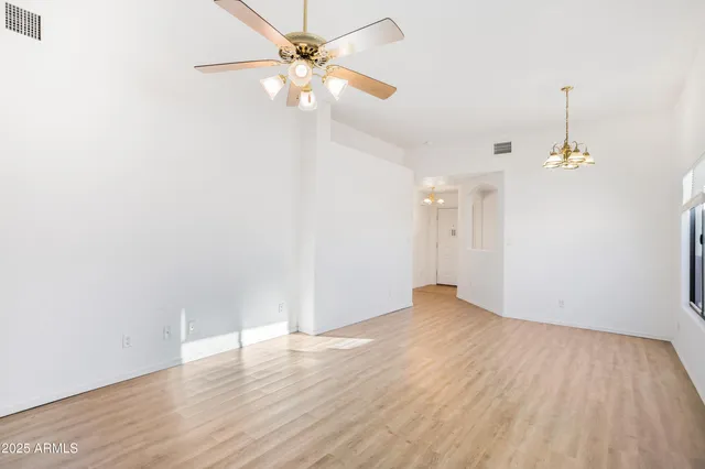 an empty room with wooden floor fan and windows