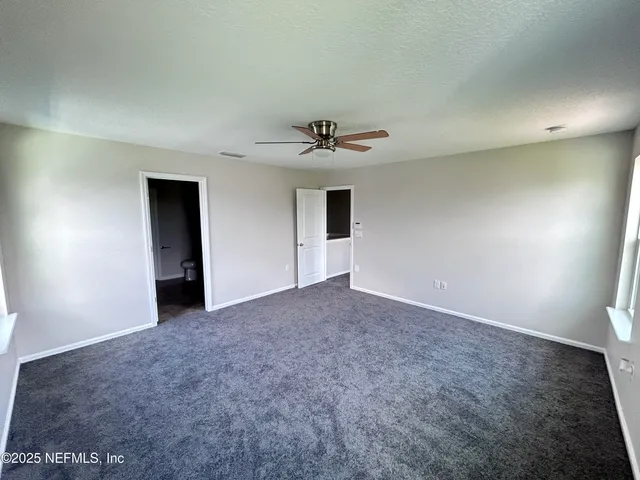 an empty room with windows and ceiling fan