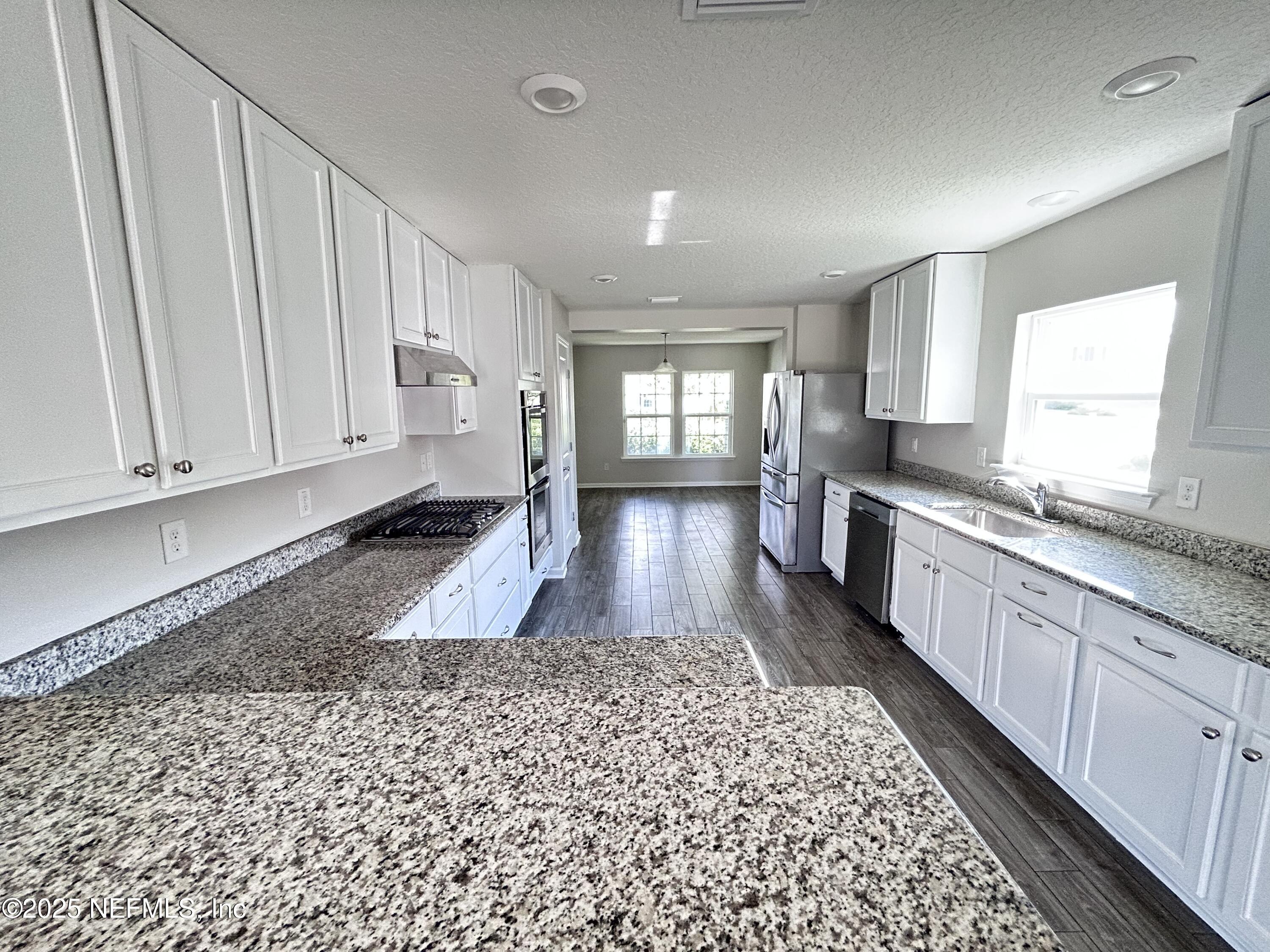 102 Bluejack Lane St. Augustine, FL 32095 - Photo 29 of 32 a large white kitchen with a stove a sink a window and white cabinets