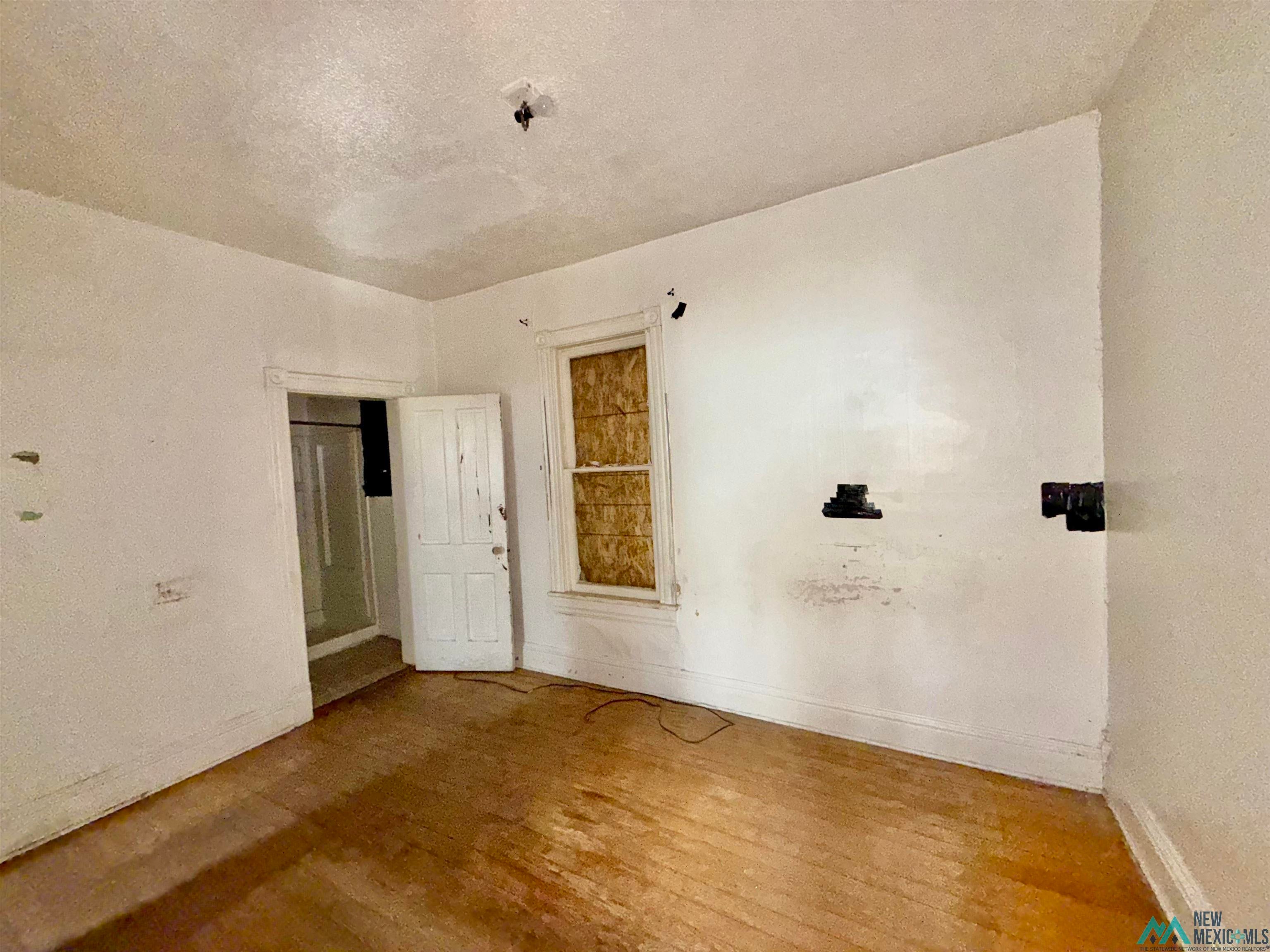 237 Vermejo Street Raton, NM 87740 - Photo 2 of 14 Spare room featuring wood finished floors and a textured ceiling