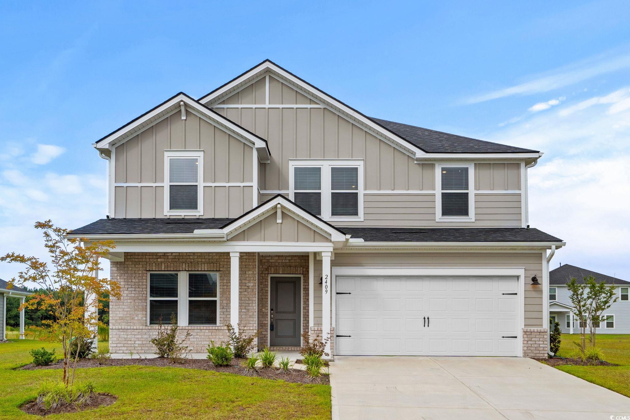 Craftsman-style house featuring board and batten siding, an attached garage, brick siding, and driveway